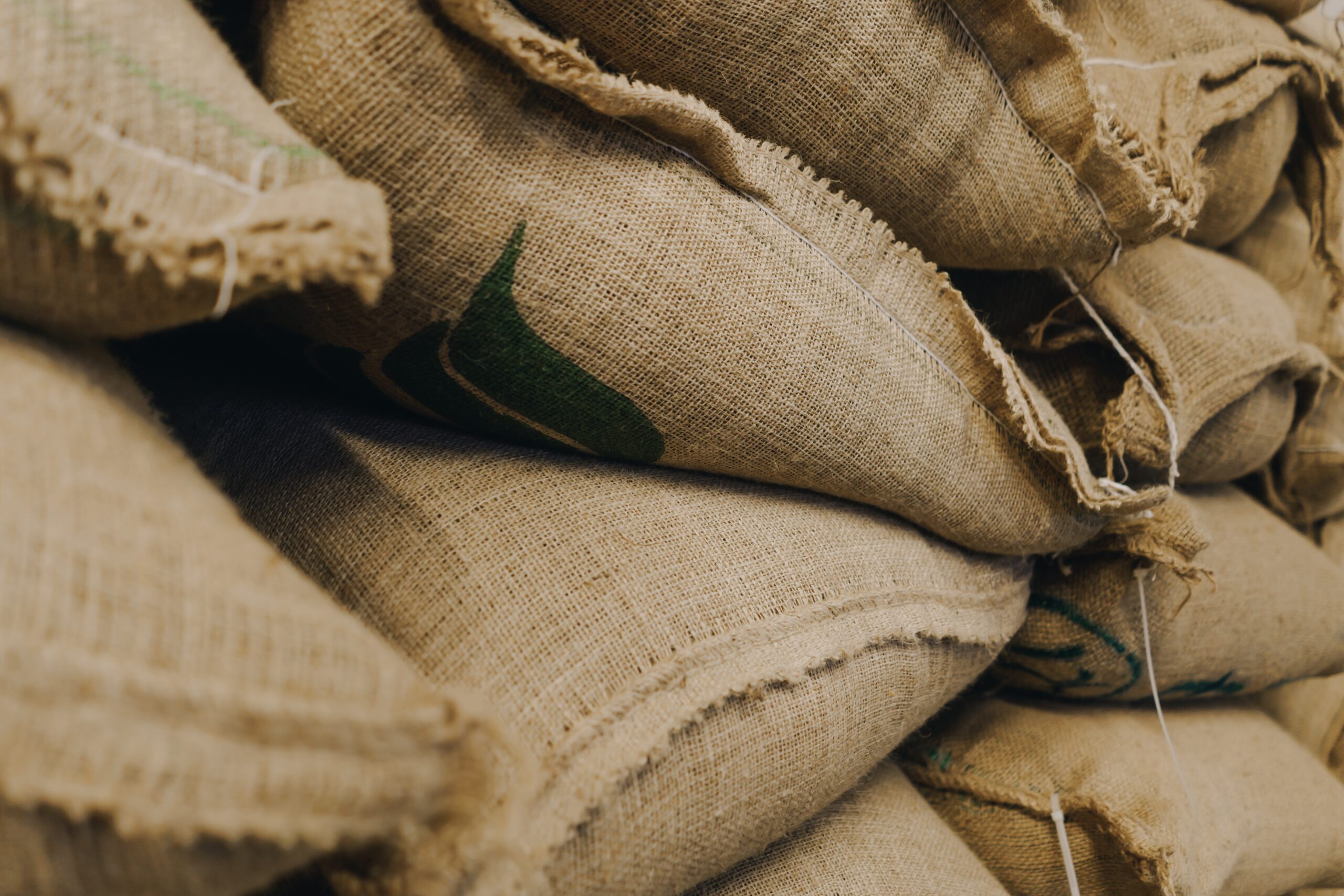 Pile,Of,Textile,Bags,Full,Of,Green,Coffee,Beans,In