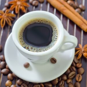 Fresh brewed cup of coffee in a white mug surrounded by specialty-grade coffee beans.