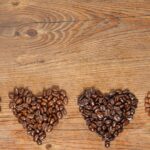 Different toasts of coffee beans gathered into four heart shapes on a board.